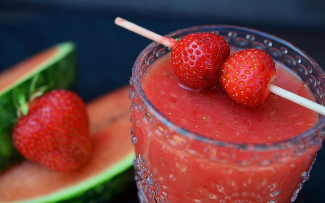 Un vaso de jugo verde intenso con hojas de espinaca
